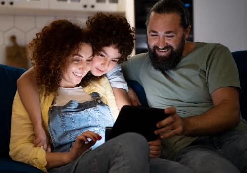 família sentada no sofá assistindo conteúdo no tablet